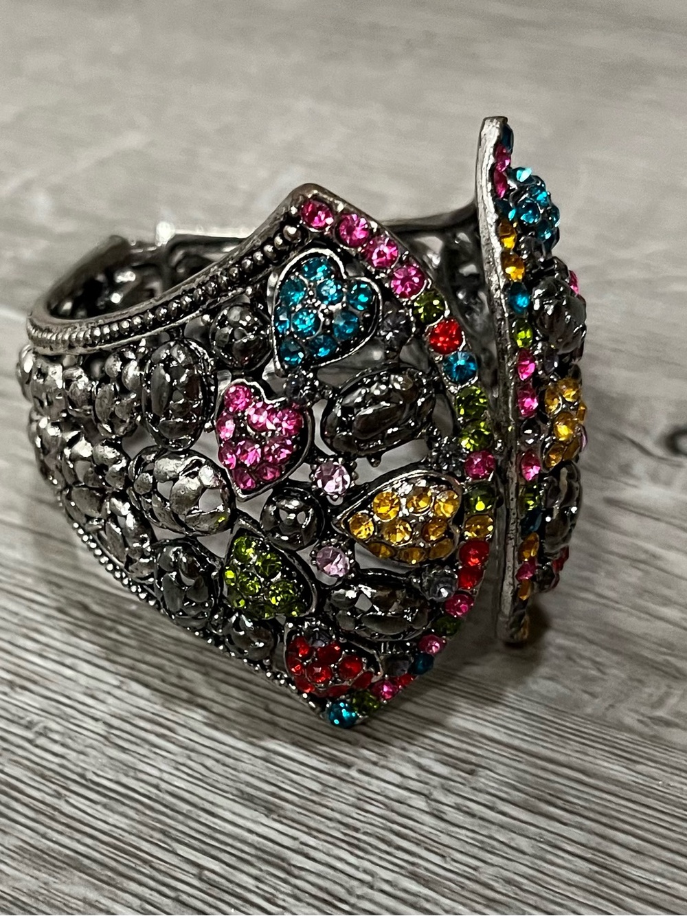 Silver-tone hinged cuff bracelet featuring colorful rhinestones